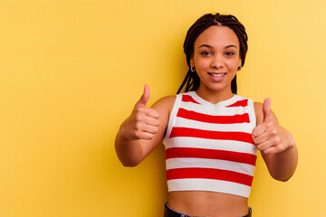 Young african american woman isolated on yellow background smiling and raising thumb up