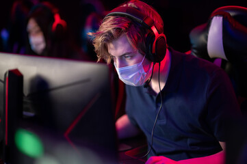 Portrait in a medical mask during the international esports games tournament. A computer geek with...