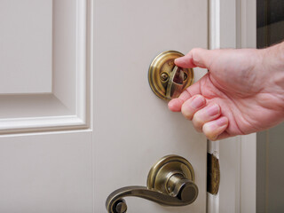Close up of man locking deadbolt door lock on white entry door. Home security burglar and robbery...