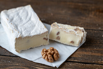 cheese with nuts on a wooden background with chopped pieces inside nuts