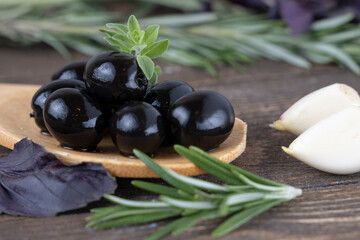 olives with spices and rosemary in a wooden spoon