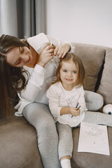 Mom braids her daughter's hair on the couch