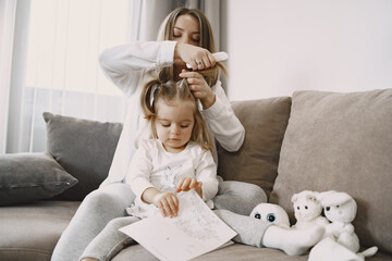 Mom braids her daughter's hair on the couch