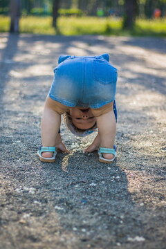 Funny playing baby standing on his head on a warm summer day