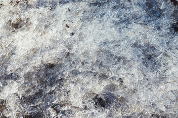Small dirty broken ice on the ground. The beginning of spring. Broken ice on the ground as a background. Winter