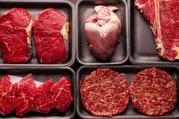 Black plastic packaging trays from supermarket with different types of fresh raw meat cuts, fresh...