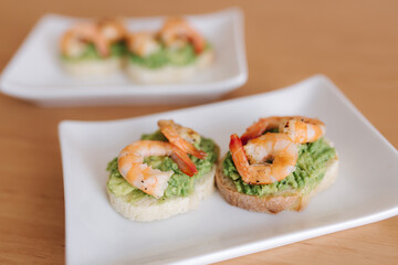 Healthy appetizer of bruschetta with guacamole shrimp closeup view. Fried shrimp and mashed avocado on a toasted bread