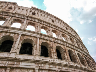 Fototapeta premium Marble arches ruins of Colosseum outside top part epic view. Iconic ancient monumental 3-tiered Roman amphitheater, gladiatorial games arena in center of Rome, Italy
