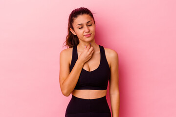 Young sport Indian woman isolated on pink background suffers pain in throat due a virus or infection.