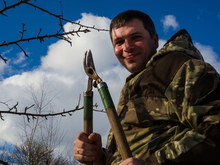 Man pruning fruit tree branches. Work in the home garden. A scene from everyday life
