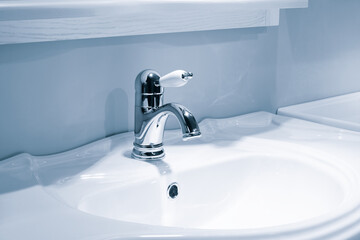 Luxury faucet mixer and white towel on a white sink in a beautiful gray bathroom. Sanitary...