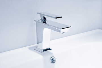 Luxury faucet mixer and white towel on a white sink in a beautiful gray bathroom. Sanitary...