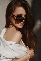 Fashion portrait of a young woman in trendy sunglasses posing outdoors on the summer sunny day