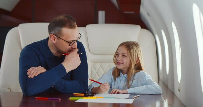 Father and daughter drawing with colorful pencils flying together on private jet