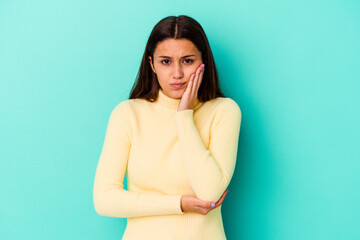Obraz premium Young Indian woman isolated on blue background blows cheeks, has tired expression. Facial expression concept.