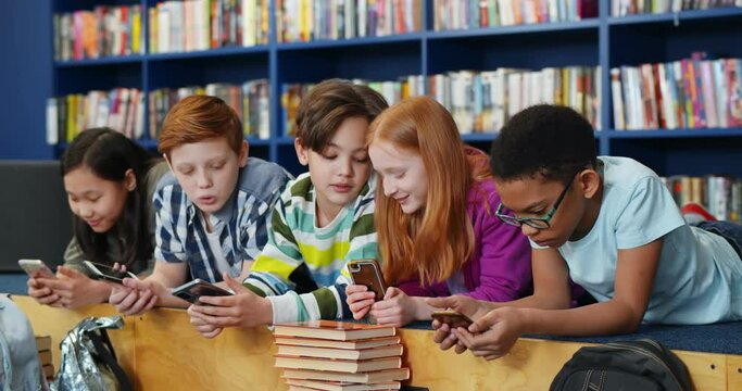 Multiethnic students using mobile phone in library at school