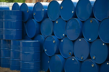 There are many round barrels in white and blue at the production site. The barrels contain oil and chemical products.