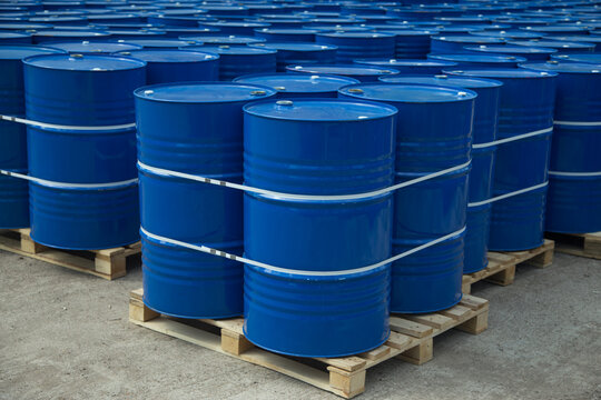 There are many round barrels in white and blue at the production site. The barrels contain oil and chemical products.