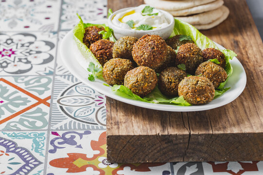 Traditional homemade chickpea falafel balls with white sauce and pita bread on whitw plate on wooden board, healthy vegetarian life concept. Israel Jewish food.