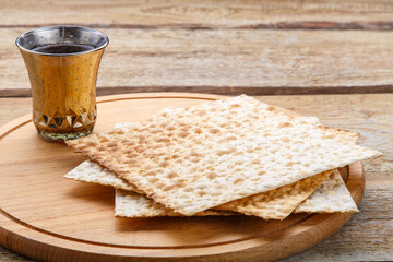 On a round wooden board matzah and a glass of kiddush wine.