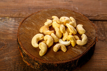 Cashew nuts scattered on a round board on a wooden table.