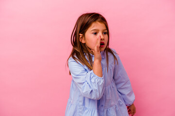Little caucasian girl isolated on pink background  is saying a secret hot braking news and looking...