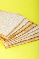 Fragment of matzo several sheets one on top of the other on a yellow background.