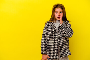 Little caucasian girl isolated on yellow background is saying a secret hot braking news and looking...