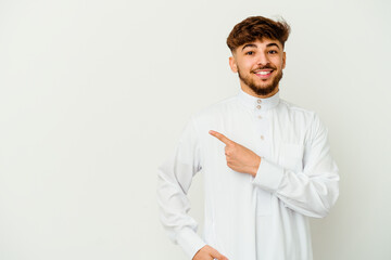 Young Moroccan man wearing a typical arab clothes isolated on white background smiling and pointing aside, showing something at blank space.