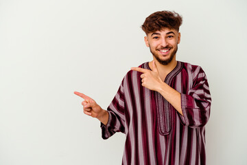 Fototapeta premium Young Moroccan man isolated on white background pointing with forefingers to a copy space, expressing excitement and desire.