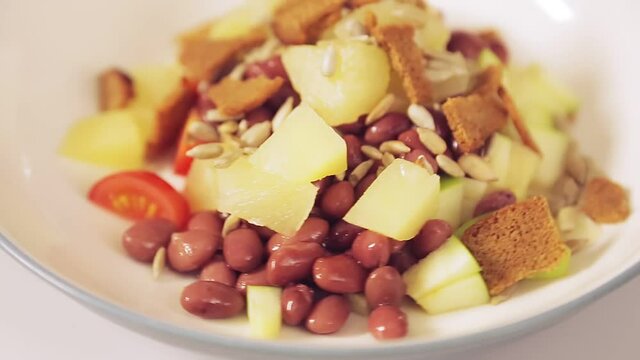 Thai salad with pineapples and seeds in a plate rotates in a circle