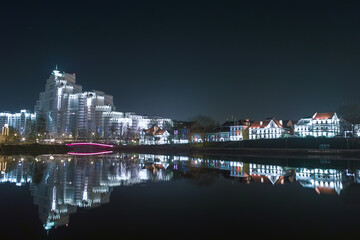 Evening city in lights, reflected in the water