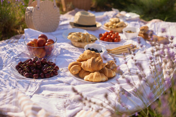 Fototapeta na wymiar summer picnic in lavender fields. still life summer outdoor picnic with bread, berry