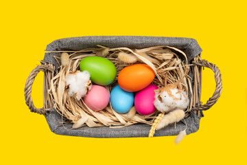 Easter Eggs in basket on yellow background