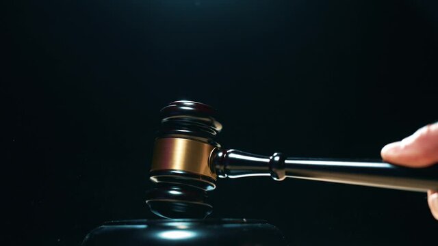 A judge is hitting gavel off a block in courtroom. Gavel is being struck to decide an auction or guilty verdict in court