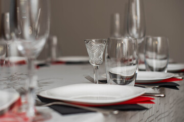 Empty glasses and plate set in restaurant. Red and black napkins.