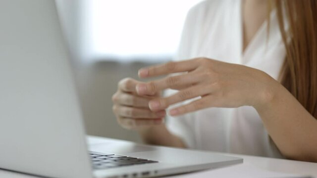 Close up hand woman texting on keyboard laptop work so hard and long time that he has office syndrome. She has wrist pain, from working with laptop sitting in office