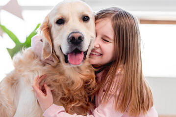 Little girl petting golden retriever dog
