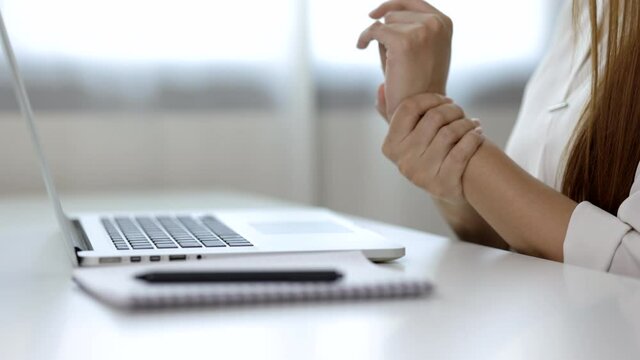 Close up hand woman texting on keyboard laptop work so hard and long time that he has office syndrome. She has wrist pain, from working with laptop sitting in office