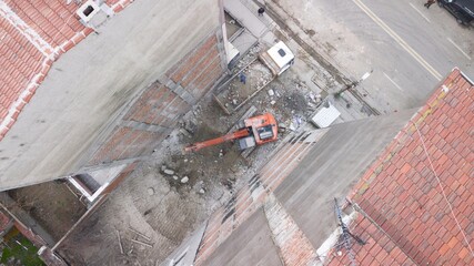 Aerial view of excavation work at the city center. Excavator is filling the land into the truck between buildings. 