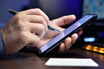 Businessman hands holding cellphone with business report and investment data.