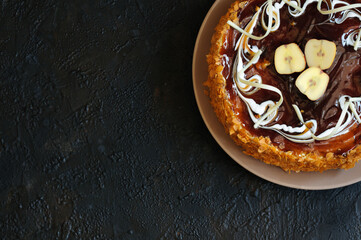 Cake with apples, caramel and white chocolate shot from above over a dark table with copy space