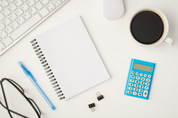 Top view photo of business workplace with keyboard mouse cup of coffee binders glasses notebook with copyspace blue calculator and pen on isolated white background