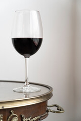 Glass of red wine on old wooden table and glass. White wall background. 