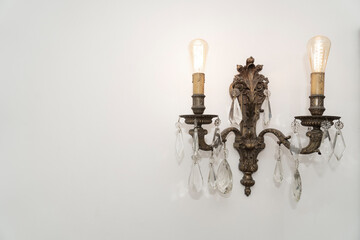 Old row chandelier hanging on a white wall. Lamps on.