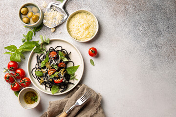 Black spaghetti with dried tomatoes,parmesan cheese,pesto,basil and fresh marjoram and different dishes for italian pasta.Top view,flat lay.