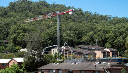 Obraz premium Concrete Boom Pump delivering material to new building site with bushland backdrop. Gosford, Australia. February 26, 2021. 56-58 Beane St. Part of a series.