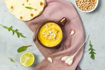 Hummus in a bowl on a gray background, with tortillas, lemon garlic and chickpeas. Top view, horizontal