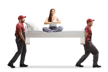 Young woman in pajamas sitting on a bed doing yoga and movers carrying the bed