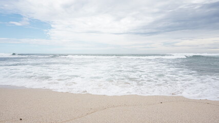 Fototapeta na wymiar Beach waves foaming on white sand